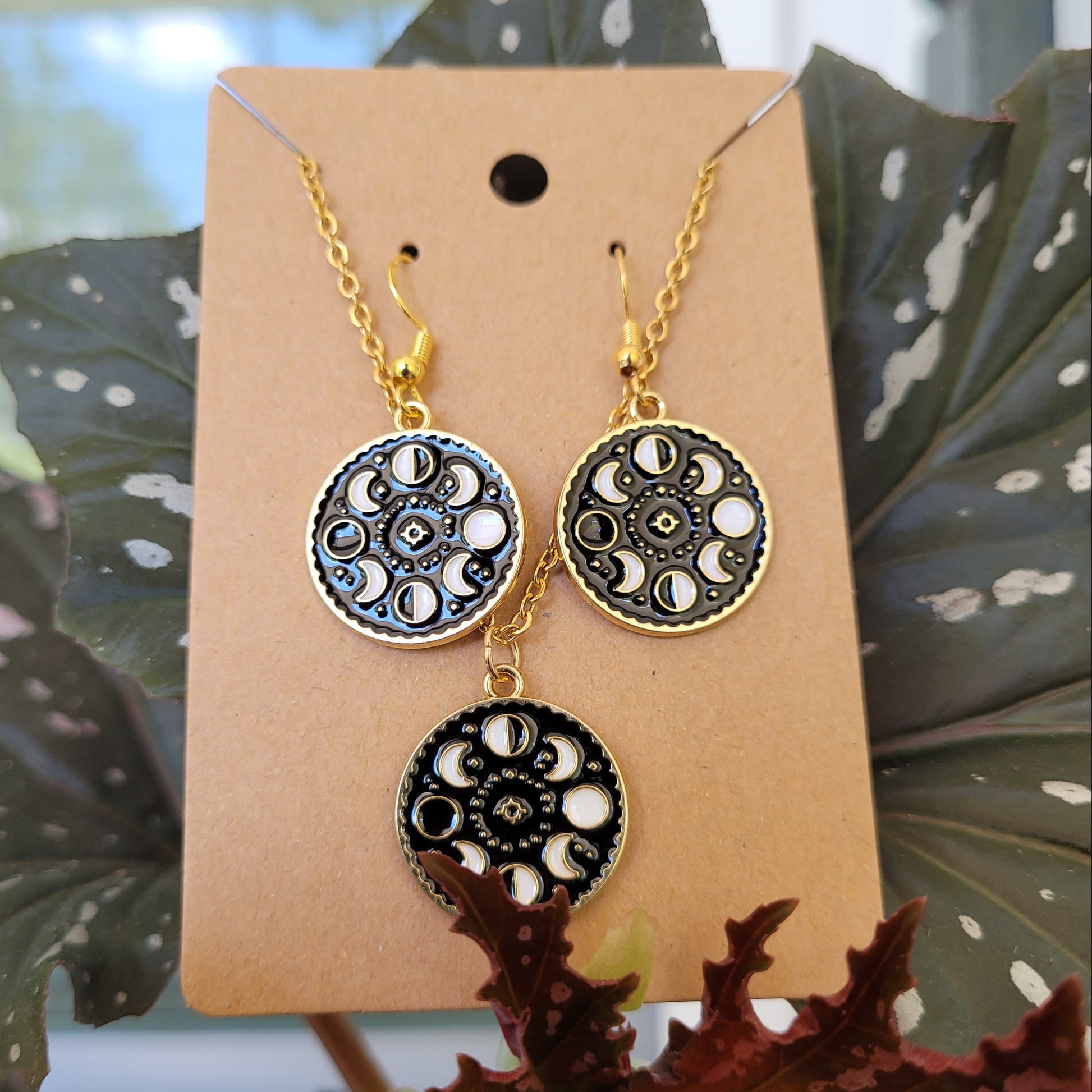 Pair of earrings on a display card with a plant in the background