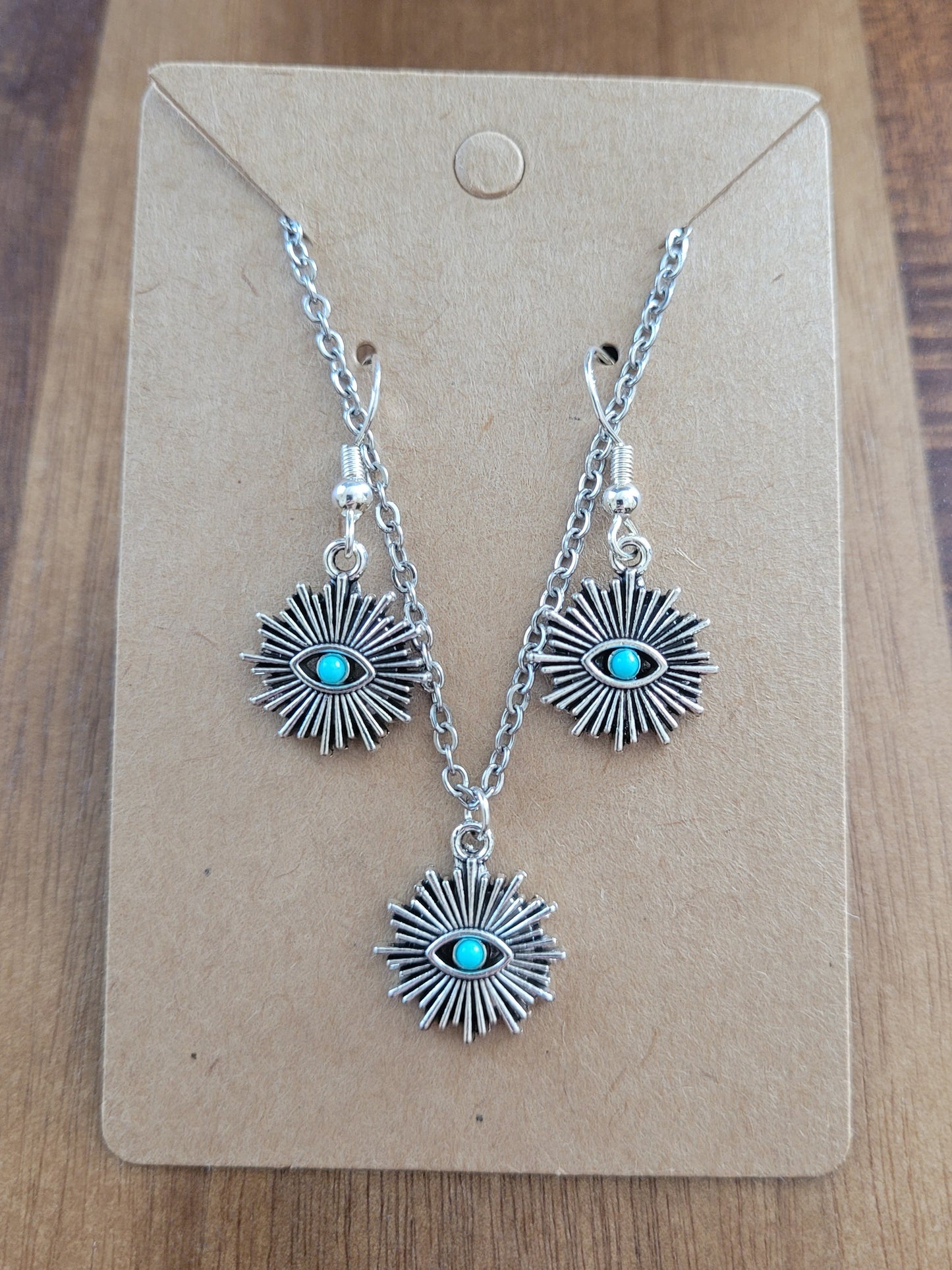 Silver earrings with turquoise stones on a brown card, placed on a wooden surface.