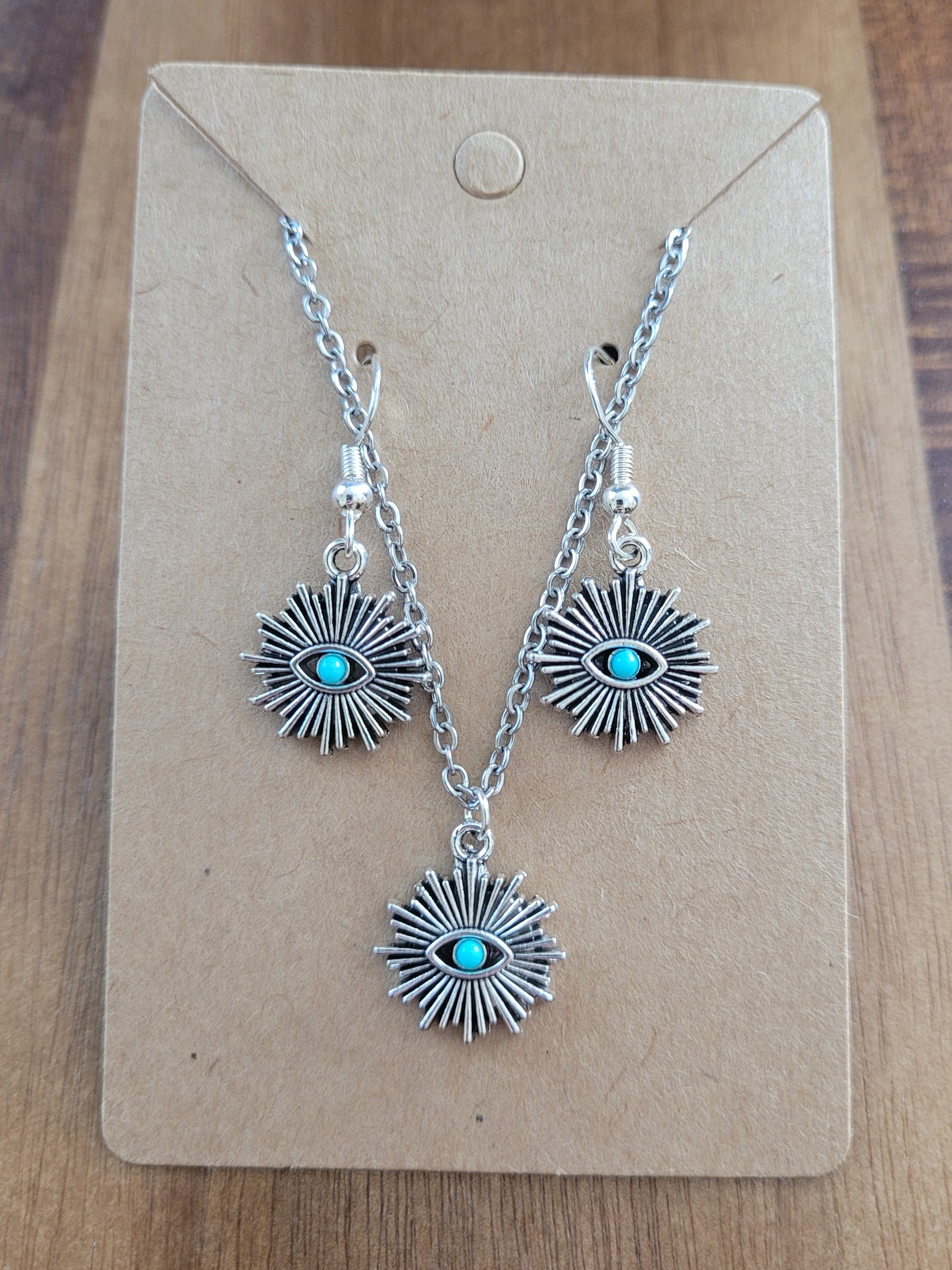 Silver earrings with turquoise stones on a brown card, placed on a wooden surface.